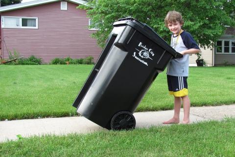 A boy and a black rubbish bin. The Thai for "a boy and a black rubbish bin" is "เด็กผู้ชายและถังขยะสีดำ".