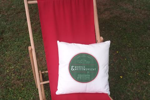 A red deckchair and a backrest pillow. The Thai for "a red deckchair and a backrest pillow" is "เก้าอี้ชายหาดสีแดงและหมอนอิง".