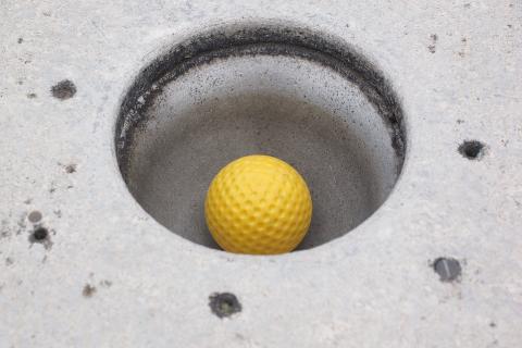 A yellow golf ball in the hole. The Thai for "a yellow golf ball in the hole" is "ลูกกอล์ฟสีเหลืองในหลุม".