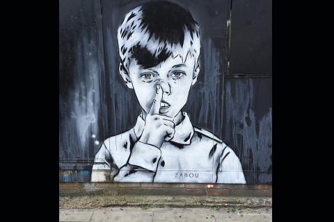 A painting of a boy on a wall. The Thai for "a painting of a boy on a wall" is "รูปวาดเด็กผู้ชายบนกำแพง".