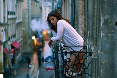 A women smokes on the balcony. The Thai for "a women smokes on the balcony" is "ผู้หญิงสูบบุหรี่บนระเบียง".