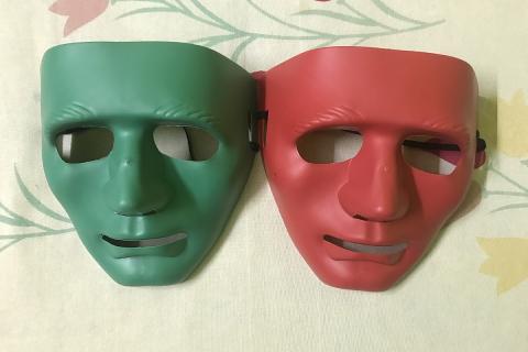 A green plastic mask and a red plastic mask. The Thai for "a green plastic mask and a red plastic mask" is "หน้ากากพลาสติกสีเขียวและหน้ากากพลาสติกสีแดง".