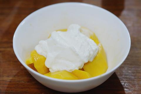 Mango and yogurt in a white bowl. The Thai for "mango and yogurt in a white bowl" is "มะม่วงกับโยเกิร์ตในชามสีขาว".