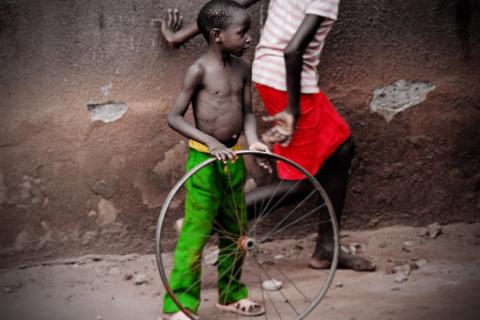 A boy with a bicycle wheel. The Thai for "a boy with a bicycle wheel" is "เด็กผู้ชายกับล้อรถจักรยาน".