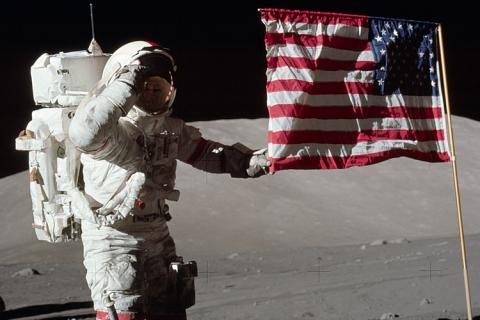 An astronaut with an American flag. The Thai for "an astronaut with an American flag" is "นักบินอวกาศกับธงชาติอเมริกา".