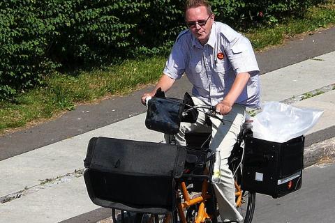 A postman on a bicycle. The Thai for "a postman on a bicycle" is "บุรุษไปรษณีย์บนรถจักรยาน".