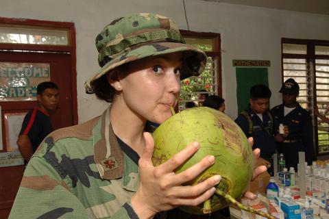 A female soldier is drinking coconut juice.. The Thai for "A female soldier is drinking coconut juice." is "ทหารหญิงกำลังดื่มน้ำมะพร้าว".