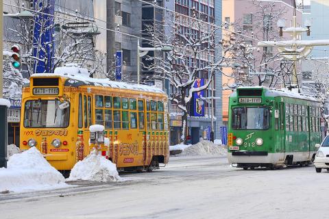 A yellow tram and a green tram. The Thai for "a yellow tram and a green tram" is "รถรางสีเหลืองและรถรางสีเขียว".