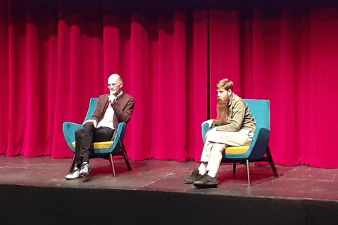 Two men on stage. The Thai for "two men on stage" is "ผู้ชายสองคนบนเวที".