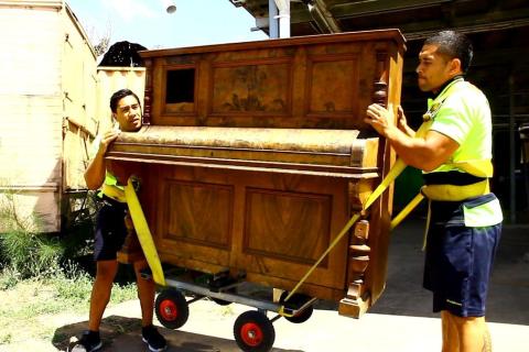 Two men are moving a piano. The Thai for "two men are moving a piano" is "ชายสองคนกำลังย้ายเปียโน".