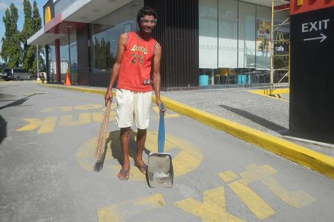 A man carrying a broom and a dustpan. The Thai for "a man carrying a broom and a dustpan" is "ผู้ชายถือไม้กวาดและที่ตักผง".