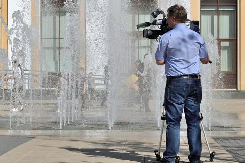 A photographer at a fountain. The Thai for "a photographer at a fountain" is "ช่างภาพที่น้ำพุ".