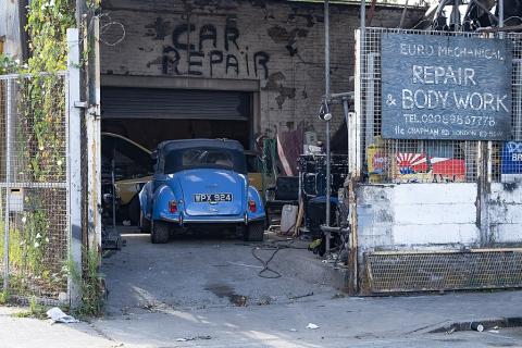 A blue car in a repair shop. The Thai for "a blue car in a repair shop" is "รถยนต์สีน้ำเงินในอู่ซ่อมรถ".