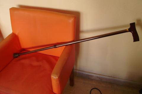 A cane on an armchair. The Thai for "a cane on an armchair" is "ไม้เท้าบนเก้าอี้นวม".