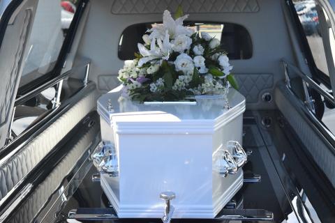 A white bouquet on a white coffin. The Thai for "a white bouquet on a white coffin" is "ช่อดอกไม้สีขาวบนโลงศพสีขาว".