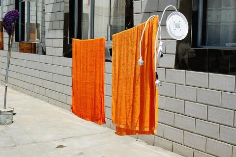 Two orange towels on a clothesline. The Thai for "two orange towels on a clothesline" is "ผ้าเช็ดตัวสีส้มสองผืนบนราวตากผ้า".