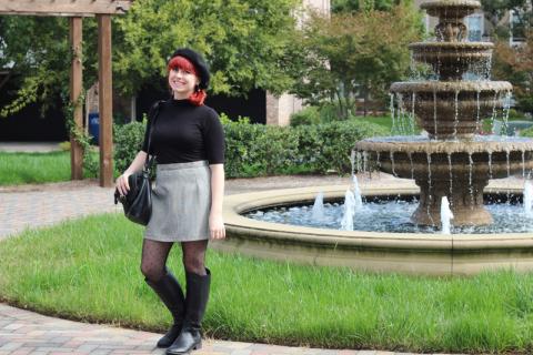 A woman carrying a black bag in front of a fountain. The Thai for "a woman carrying a black bag in front of a fountain" is "ผู้หญิงสะพายกระเป๋าสีดำที่หน้าน้ำพุ".