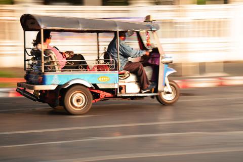 A tuk-tuk driving on the road. The Thai for "a tuk-tuk driving on the road" is "ตุ๊ก ตุ๊กวิ่งบนถนน".