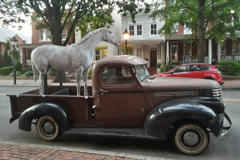 A statue of a horse on a pickup truck. The Thai for "a statue of a horse on a pickup truck" is "รูปปั้นม้าบนรถปิ๊คอัพ".