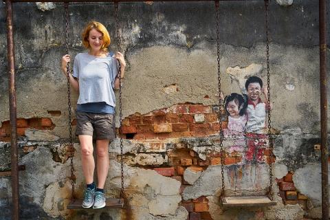 A woman standing on a swing. The Thai for "a woman standing on a swing" is "ผู้หญิงยืนบนชิงช้า".