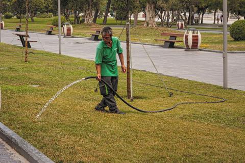 A gardener watering the lawn. The Thai for "a gardener watering the lawn" is "คนสวนรดน้ำสนามหญ้า".