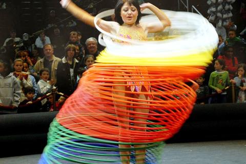 A woman twirling a lot of hula hoops. The Thai for "a woman twirling a lot of hula hoops" is "ผู้หญิงหมุนฮูลาฮูปจำนวนมาก".