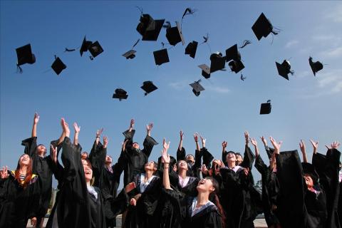 A group of graduates tossing their hats. The Thai for "a group of graduates tossing their hats" is "กลุ่มบัณฑิตโยนหมวกของพวกเขา".