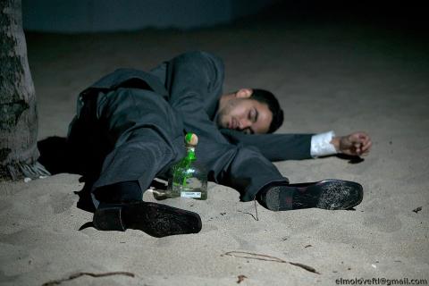 A drunk man sleeping on the beach. The Thai for "a drunk man sleeping on the beach" is "คนเมาหลับบนชายหาด".