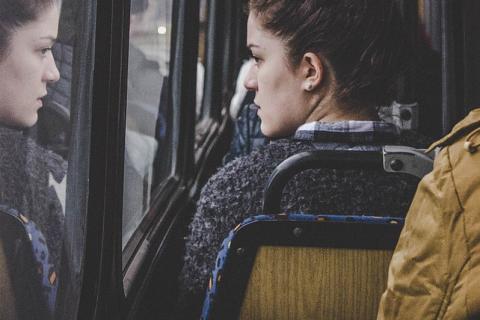 A woman looking out of a bus window. The Thai for "a woman looking out of a bus window" is "ผู้หญิงมองไปนอกหน้าต่างรถเมล์".