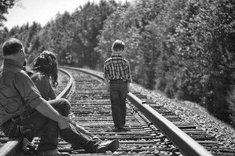 A boy with his parents on the railroad. The Thai for "a boy with his parents on the railroad" is "เด็กผู้ชายกับพ่อแม่ของเขาบนทางรถไฟ".