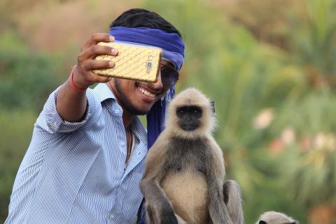 A man and a monkey take a selfie. The Thai for "a man and a monkey take a selfie" is "ผู้ชายและลิงถ่ายเซลฟี่".