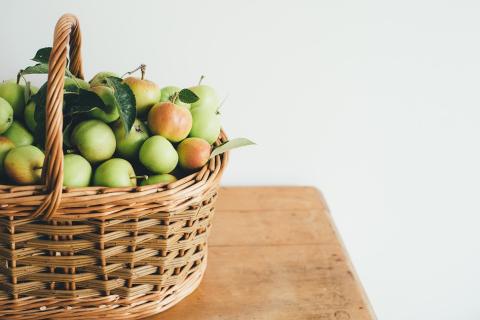 A basket of apples on the table. The Thai for "a basket of apples on the table" is "แอปเปิ้ลหนึ่งตะกร้าบนโต๊ะ".