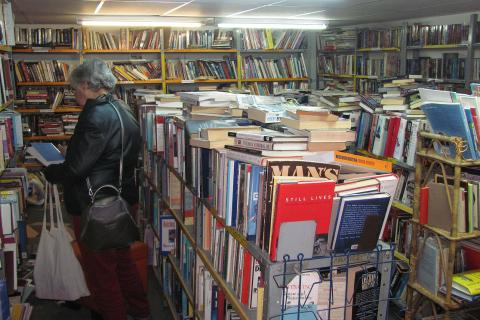 An old woman in a second-hand bookstore. The Thai for "an old woman in a second-hand bookstore" is "หญิงชราในร้านหนังสือมือสอง".