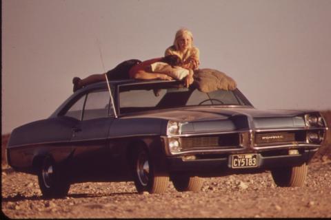 A man and a woman sunbathing on the roof of a car. The Thai for "a man and a woman sunbathing on the roof of a car" is "ผู้ชายและผู้หญิงอาบแดดบนหลังคารถ".