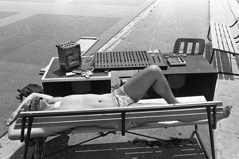 A man sunbathing on a bench. The Thai for "a man sunbathing on a bench" is "ผู้ชายอาบแดดบนม้านั่ง".