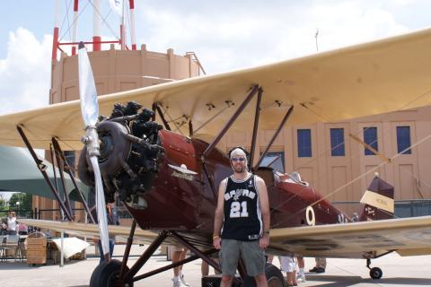 A man standing in front of a small plane. The Thai for "a man standing in front of a small plane" is "ผู้ชายยืนอยู่หน้าเครื่องบินเล็ก".