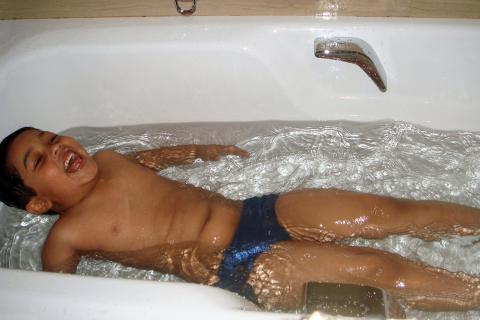 A boy having fun in a bathtub. The Thai for "a boy having fun in a bathtub" is "เด็กผู้ชายสนุกอยู่ในอ่างอาบน้ำ".