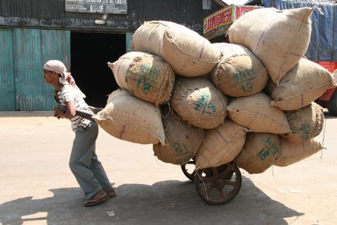 A worker dragging a load of sacks. The Thai for "a worker dragging a load of sacks" is "คนงานลากกองกระสอบ".