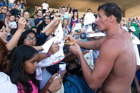 A swimmer is signing autographs. The Thai for "a swimmer is signing autographs" is "นักว่ายน้ำกำลังแจกลายเซ็น".
