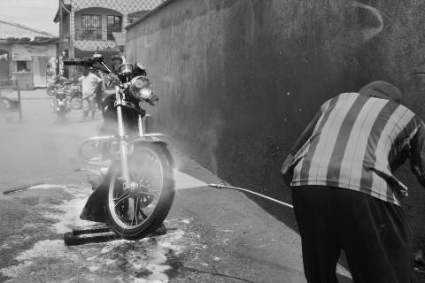 A man is washing his motorbike. The Thai for "a man is washing his motorbike" is "ผู้ชายล้างรถมอร์เตอร์ไซค์ของเขา".