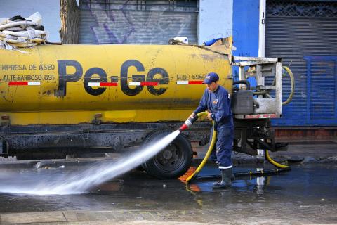 A worker washing the street. The Thai for "a worker washing the street" is "คนงานกำลังล้างถนน".