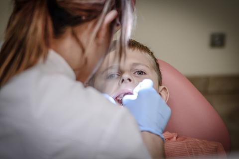 A dentist examining a boy’s teeth. The Thai for "a dentist examining a boy’s teeth" is "หมอฟันตรวจฟันของเด็กผู้ชาย".
