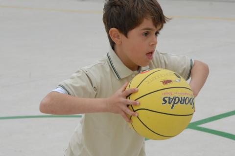 A boy holding a yellow basketball. The Thai for "a boy holding a yellow basketball" is "เด็กผู้ชายถือลูกบาสเกตบอลสีเหลือง".