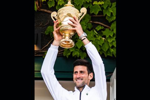 A tennis player holds up a trophy. The Thai for "a tennis player holds up a trophy" is "นักเทนนิสชูถ้วยรางวัล".