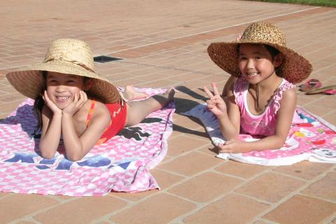 Two girls wearing straw hats. The Thai for "two girls wearing straw hats" is "เด็กผู้หญิงใส่หมวกฟางสองคน".