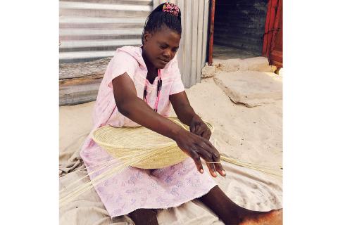 A woman weaving a basket. The Thai for "a woman weaving a basket" is "ผู้หญิงกำลังสานตะกร้า".