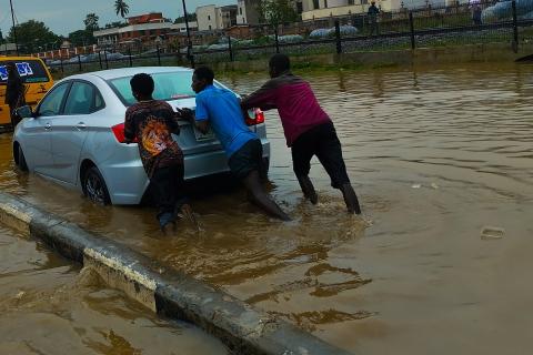 Three men pushing a car in a flood. The Thai for "three men pushing a car in a flood" is "ผู้ชายสามคนเข็นรถในน้ำท่วม".