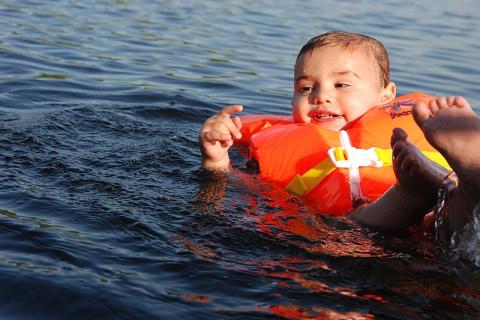 A boy is wearing a life jacket. The Thai for "a boy is wearing a life jacket" is "เด็กผู้ชายใส่เสื้อชูชีพ".