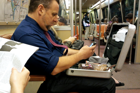 A man opening his briefcase on the metro. The Thai for "a man opening his briefcase on the metro" is "ผู้ชายเปิดกระเป๋าเอกสารของเขาบนรถไฟฟ้า".