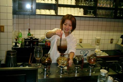 The woman is making coffee. The Thai for "the woman is making coffee" is "ผู้หญิงกำลังชงกาแฟ".